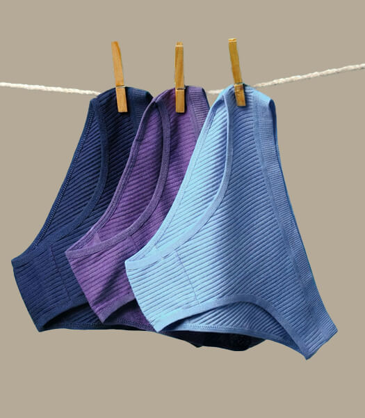 Guide showing period pants being air-dried on a rack at room temperature with good airflow, avoiding tumble dryers and direct heat to maintain absorbency and material quality.